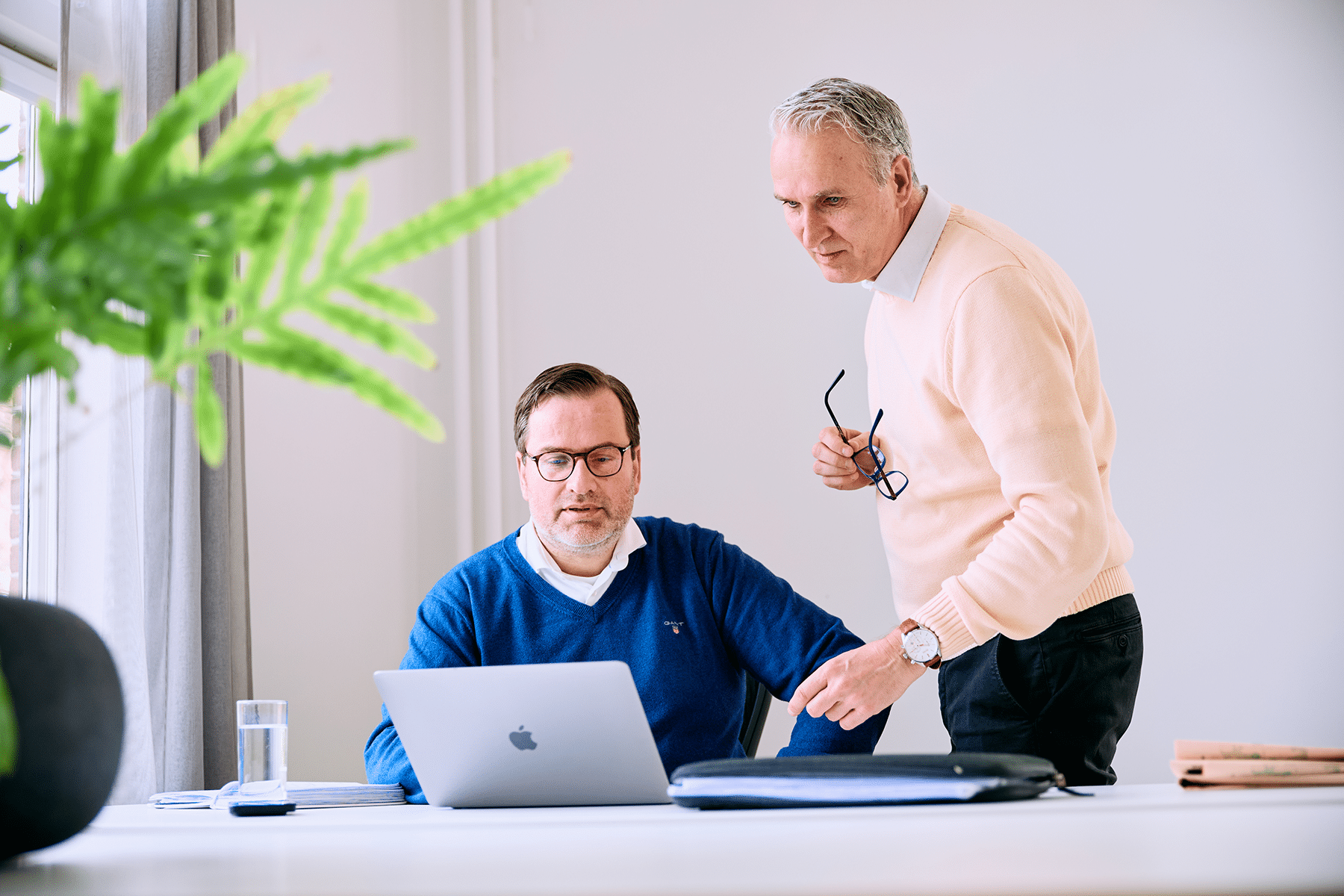 Twee collega's van ARC People aan de laptop, een van hen staat en wijst